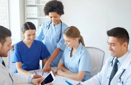 Group of healthcare professionals in scrubs and lab coats collaborating around a table