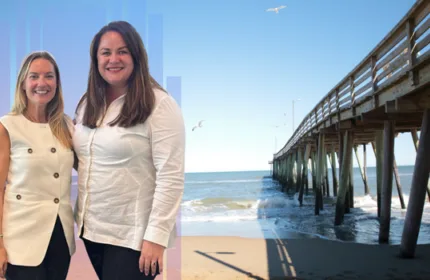 Two Beacon Hill Associates team members standing together with the Virginia Beach pier and ocean in the background
