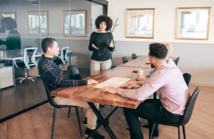 Three professionals collaborating at a conference table in a modern office during a business meeting