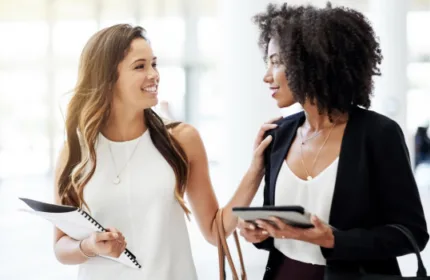 Two coworkers walk while holding work documents, image represents Beacon Hill being named as one of the largest IT staffing firms in the US