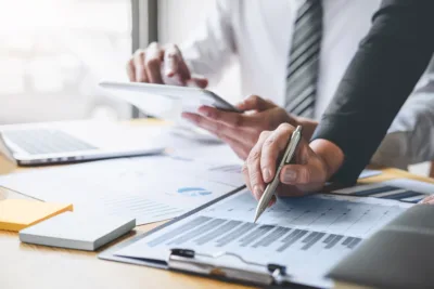 Business professionals reviewing workforce data on a tablet and printed charts, analyzing contingent labor metrics during a meeting.