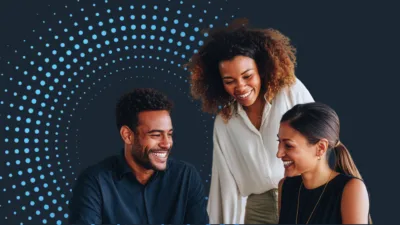 Business professionals collaborating around a laptop with abstract data points and a modern digital background, representing cautious optimism in the labor market.