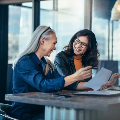 Two professionals seated at a table reviewing a document together in an office, representing streamlined implementation and effective change management for large biopharma organizations.