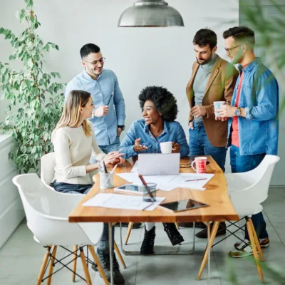 Five professionals gathered around a table with a laptop and documents, actively discussing insights, representing market intelligence, collaboration, and informed decision making for LPCs and LMHCs.