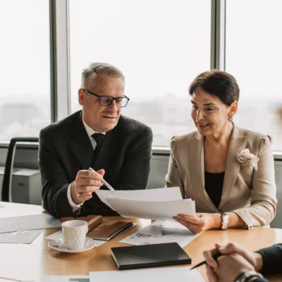 Two professionals seated at a desk reviewing printed documents together, representing regulatory affairs submission processes and ensuring accurate compliance documentation.