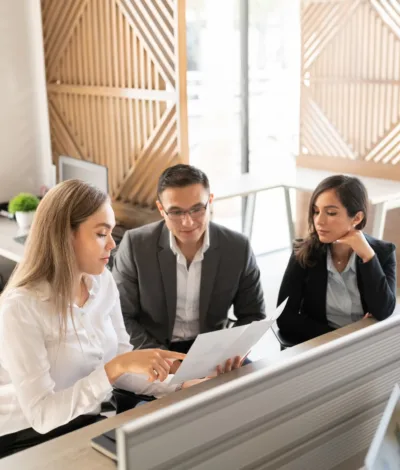 Three legal professionals reviewing documents together at a desk in a modern office setting.