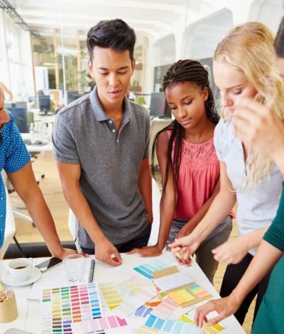 A team of creative professionals reviewing color palettes and design materials at a table.