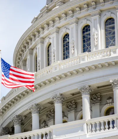 Close‑up of the U.S. Capitol dome with the American flag flying in the foreground