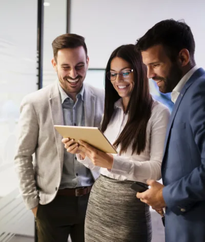 Group of legal professionals standing together and examining case documents on a tablet in a professional office environment