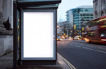 Blank illuminated advertising board at a city bus stop with traffic passing by, representing outdoor marketing and creative advertising — Beacon Hill Associates staffing for advertising and marketing support roles.