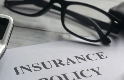 Insurance policy document with glasses and pen on a desk, representing insurance specialty services by BH Technologies.