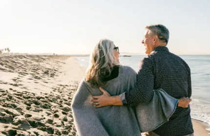 Two people walking together along a sunny beach, symbolizing life and annuity planning with BH FInancial.
