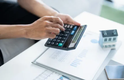 A professional using a calculator and reviewing reports, representing administrative support for investment management firms.
