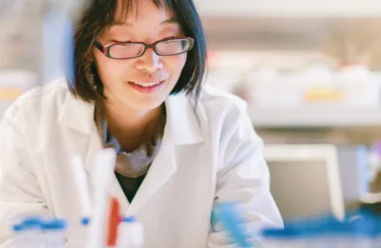 A smiling lab professional at work, representing administrative and project coordination in life sciences.