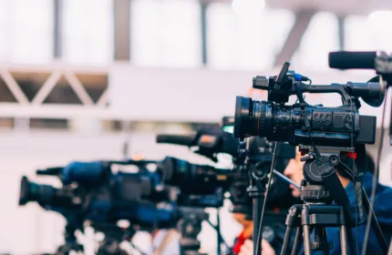 Video cameras in a studio, representing administrative and production support in the media industry.