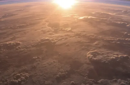 A zoomed-in image of the Earth with the sun appearing behind it.
