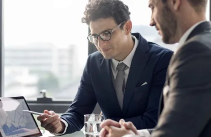 Two business professionals meeting and analyzing charts on a laptop while discussing project strategy — Beacon Hill Associates staffing for administrative and business advisory support roles.