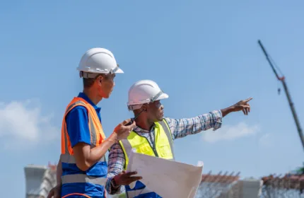 Team reviewing blueprints on site, representing administrative and project coordination support