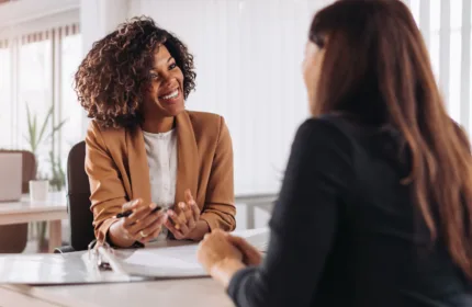 Two professionals meeting at a desk, representing consulting and administrative expertise.