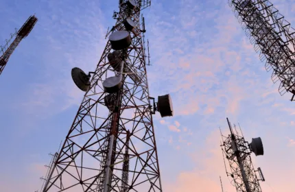 Telecom towers against a partly cloudy blue sky with a sunset creeping up from the bottom