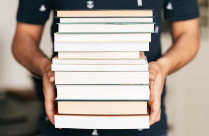Publishing professional holding a stack of books.