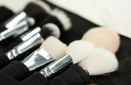 Close-up of several makeup brushes with soft white bristles arranged in a black brush holder.