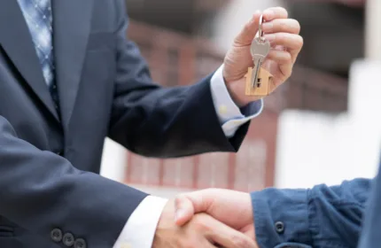 A person handing over keys, representing financial and operational support in property management.