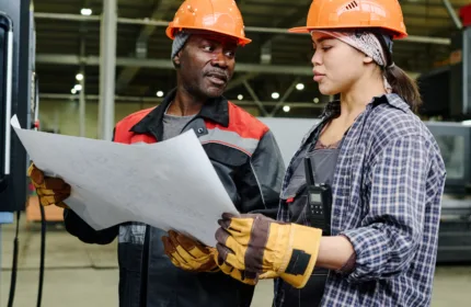 Professionals in hard hats reviewing plans, representing financial oversight in construction and facility management.