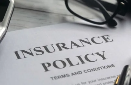 Insurance policy document with glasses and pen on a desk, representing insurance specialty services by BH Financial.