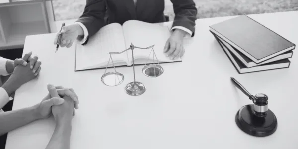 A professional presenting legal information at a desk with law books, a gavel, and scales of justice.