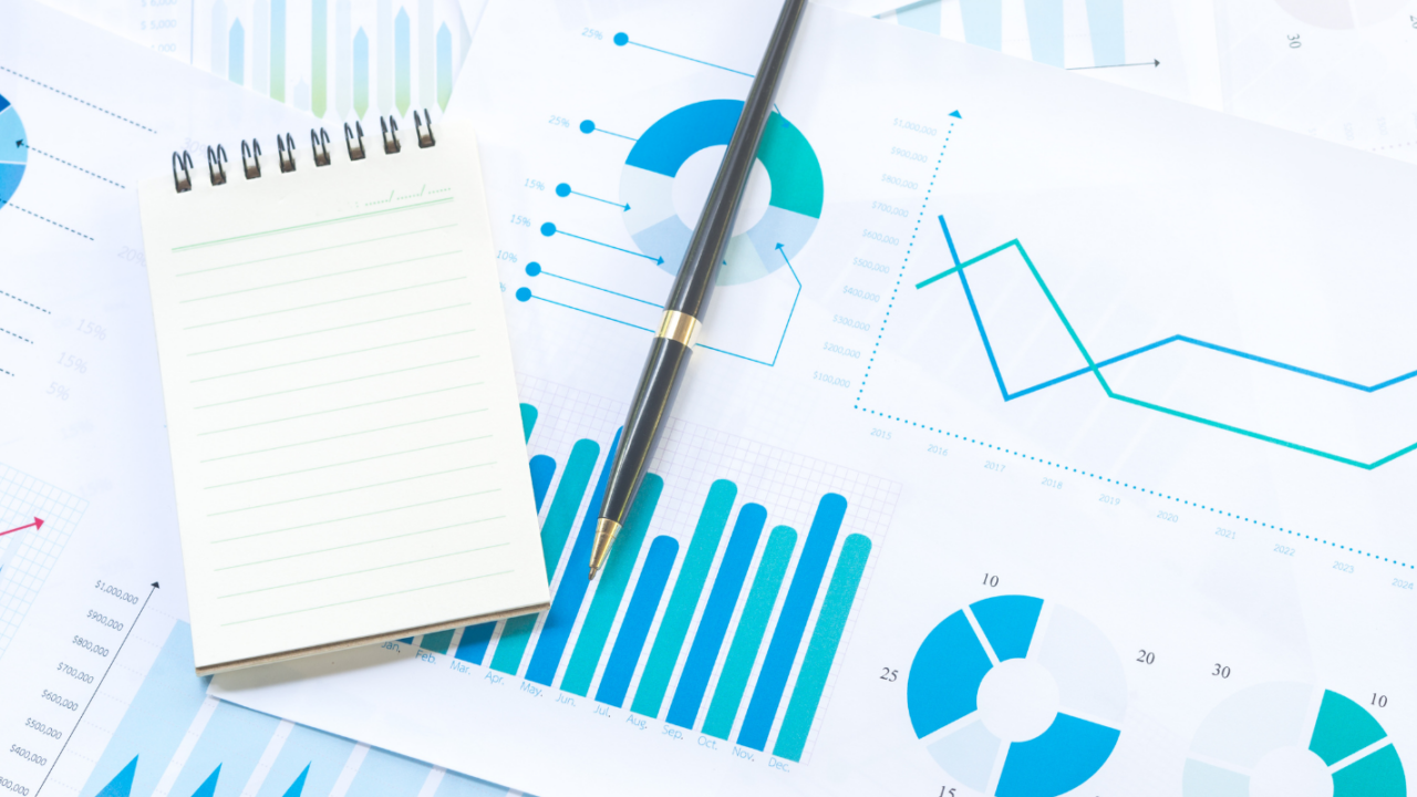 A close-up image featuring a metallic pen resting on financial documents with printed charts and numerical data. A transparent globe showing part of a world map is positioned to the left, symbolizing global finance, investment strategies, and economic analysis.