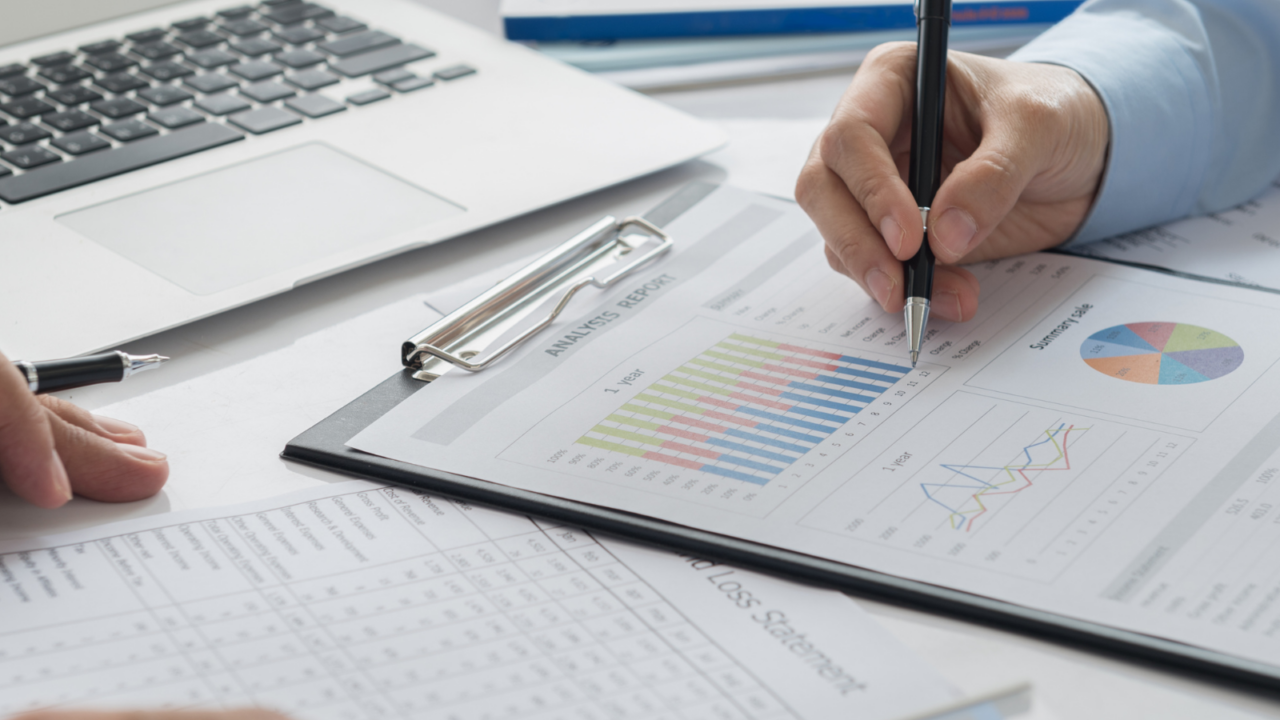Close-up of professionals reviewing financial statements and charts on a clipboard with a calculator and laptop, representing nonprofit and government accounting.