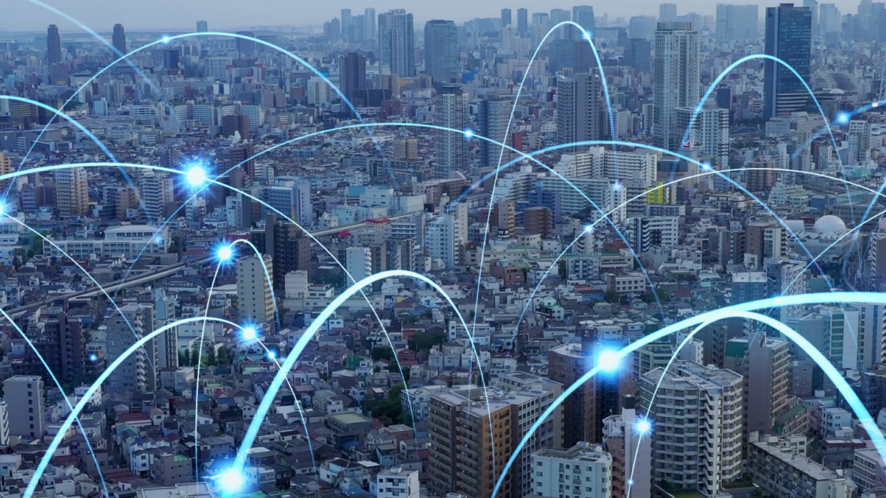 A city skyline with numerous high-rise buildings connected by glowing blue arcs and nodes, symbolizing artificial intelligence, cloud computing, and data connectivity across an urban environment.