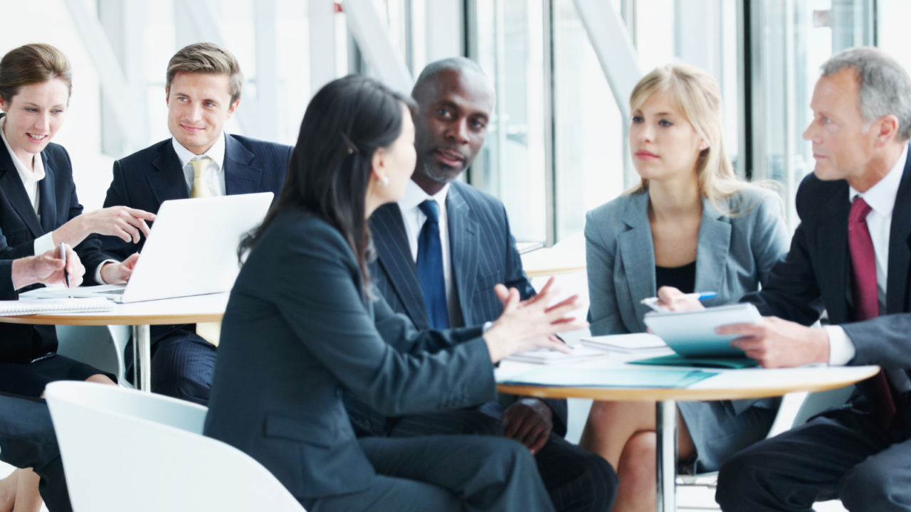An employee and labor relations professional participates in a collaborative meeting with colleagues around a table in a bright, modern office setting.