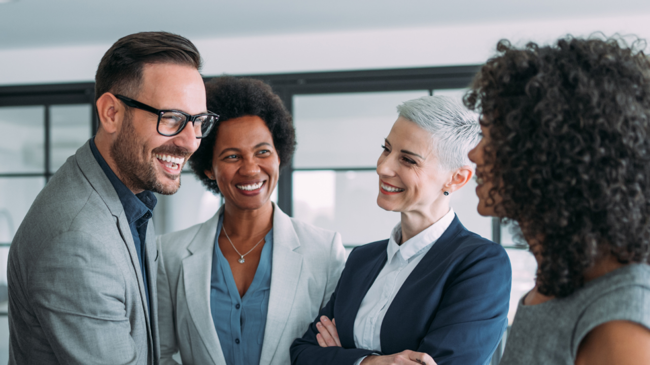 Group of business professionals in formal attire engaged in a handshake and discussion inside a modern office setting, symbolizing executive leadership, collaboration, and strategic decision-making.