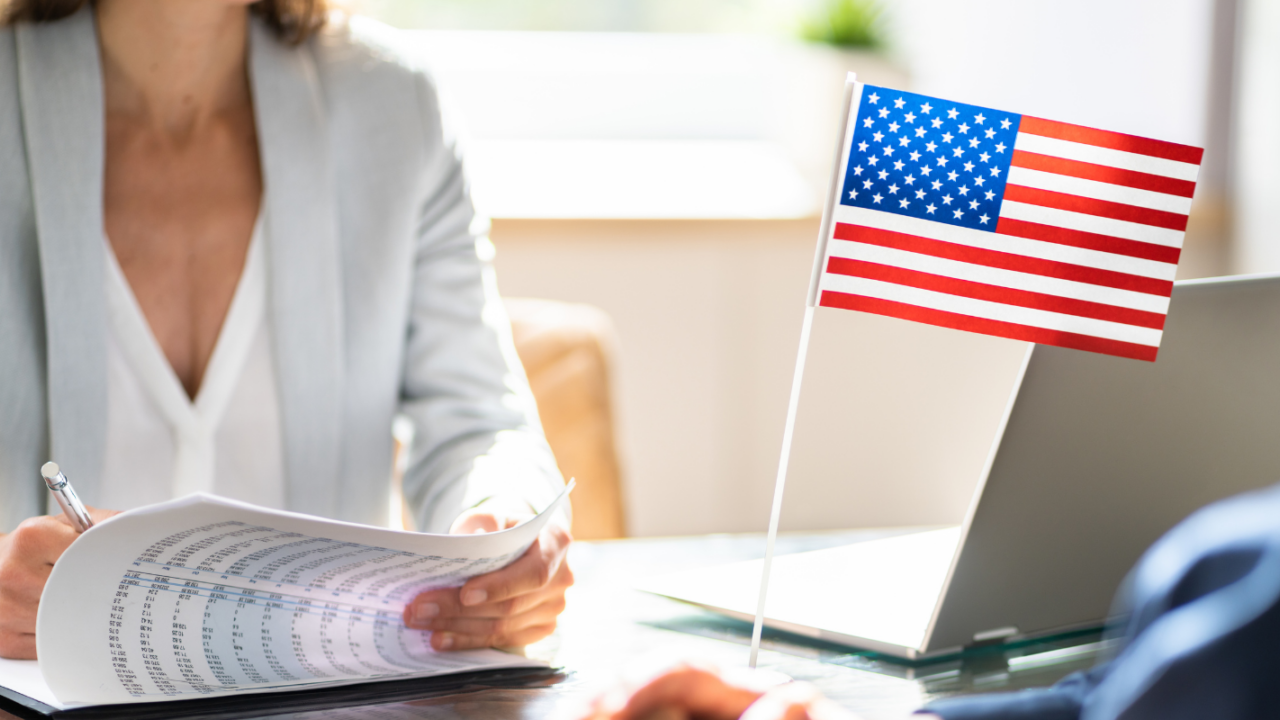 HR professional reviewing immigration documents during a consultation with a small U.S. flag on the desk