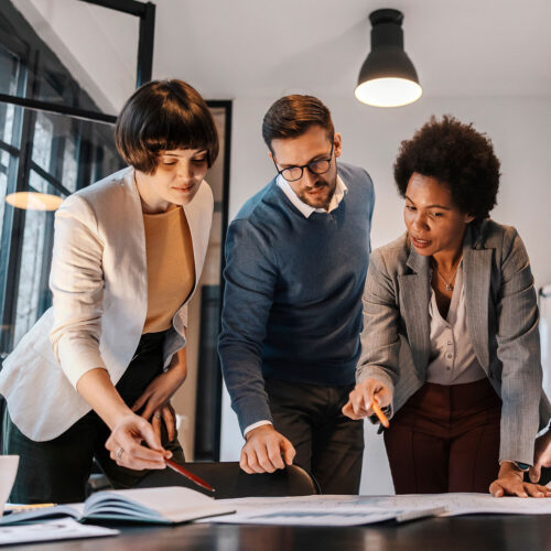 Three professionals reviewing workforce strategy documents for SOW and managed services