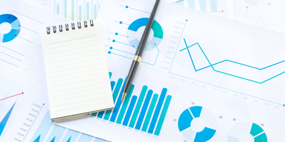 A close-up image featuring a metallic pen resting on financial documents with printed charts and numerical data. A transparent globe showing part of a world map is positioned to the left, symbolizing global finance, investment strategies, and economic analysis.