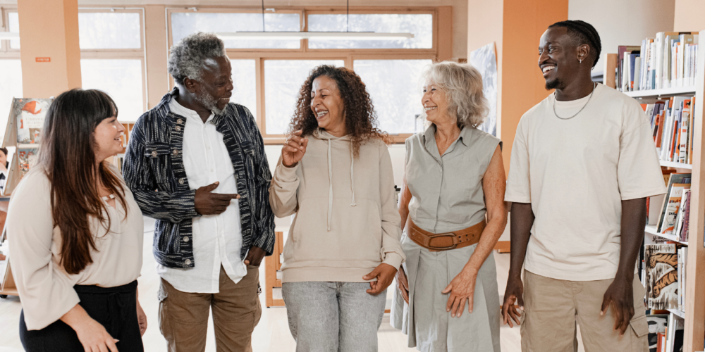 Diverse group of community members standing together in a library and sharing a conversation