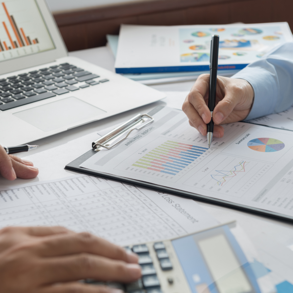 Close-up of professionals reviewing financial statements and charts on a clipboard with a calculator and laptop, representing nonprofit and government accounting.
