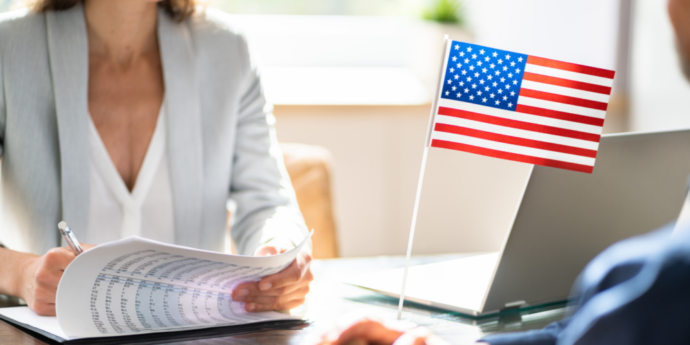 HR professional reviewing immigration documents during a consultation with a small U.S. flag on the desk