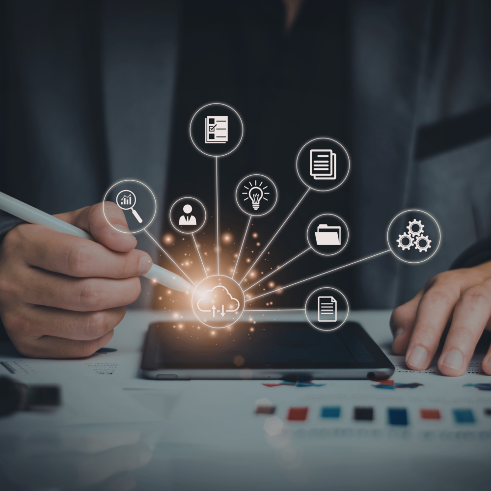 Person using a stylus on a tablet with glowing cloud icon at the center, surrounded by digital strategy elements such as analytics, user profiles, documents, lightbulb for ideas, folder, and gears representing process automation.