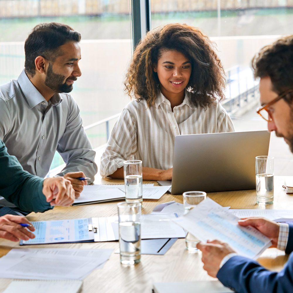 Group of professionals gathered around a conference table with laptops and documents during a team onboarding session