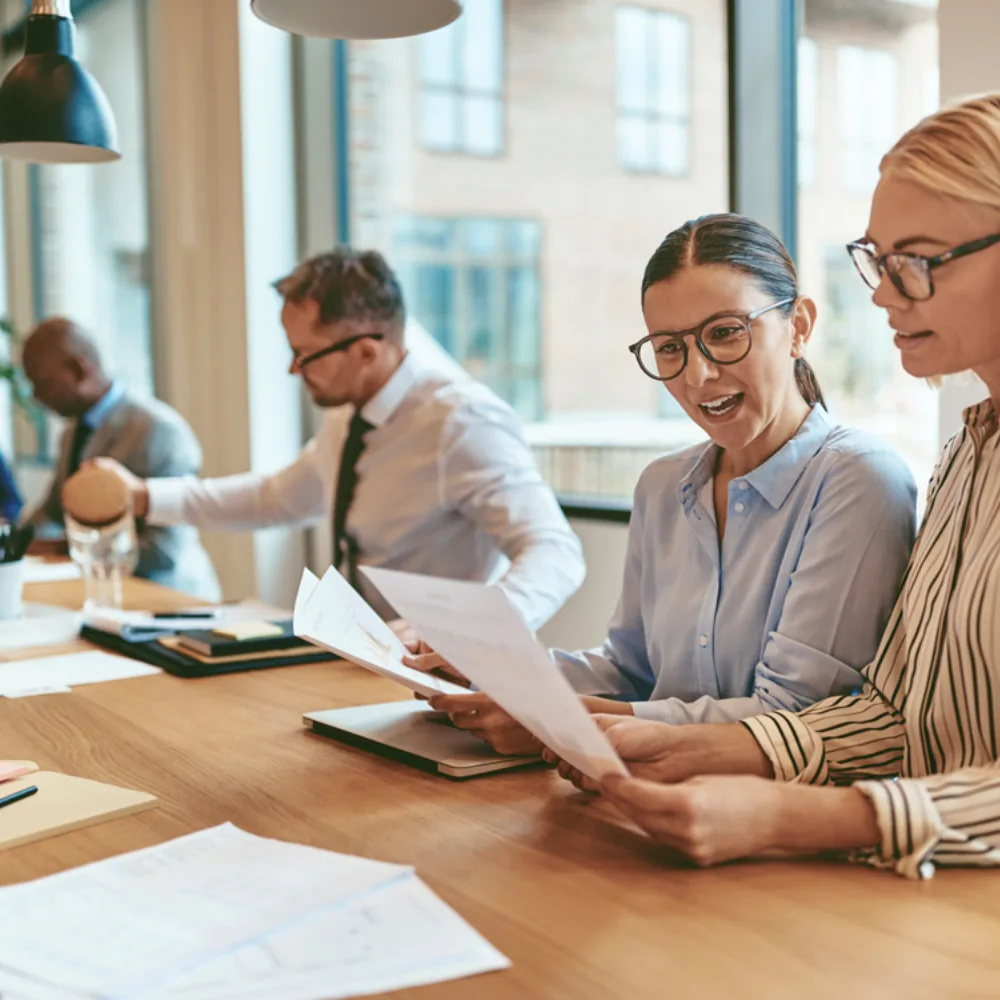 Team of finance professionals reviewing documents and discussing data at a large conference table in a bright office