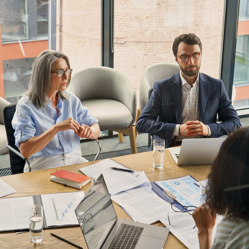 Team of finance professionals in a modern office reviewing reports and financial documents during a meeting