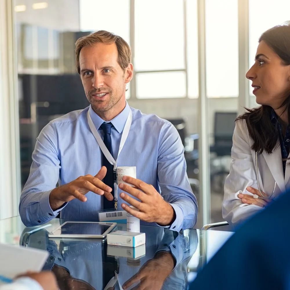 Pharmaceutical professionals in discussion around medication packaging, representing life sciences staffing and executive search