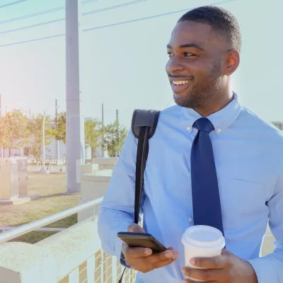 Professional man commuting with coffee and smartphone, symbolizing career mobility and workforce solutions offered by Beacon Hill, a top staffing and consulting firm.
