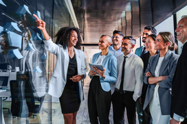 Business team collaborating in a modern office, with one professional leading a discussion using sticky notes on a glass wall