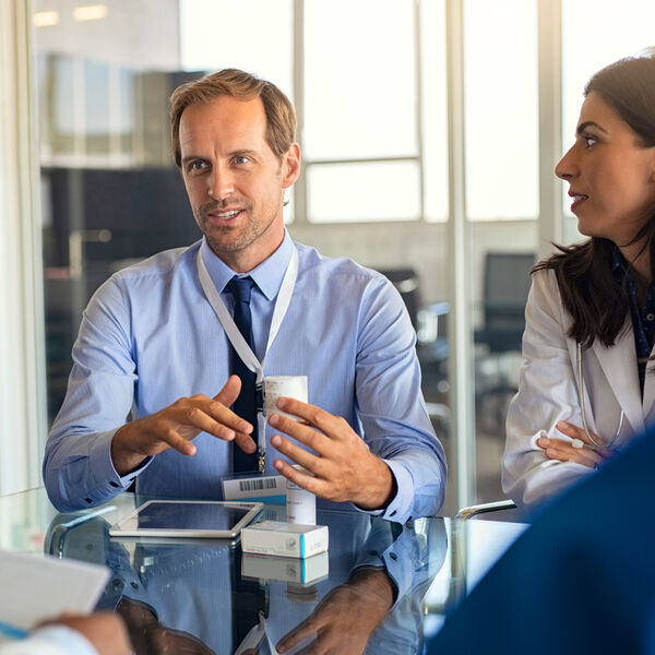 Pharmaceutical professionals in discussion around medication packaging, representing life sciences staffing and executive search